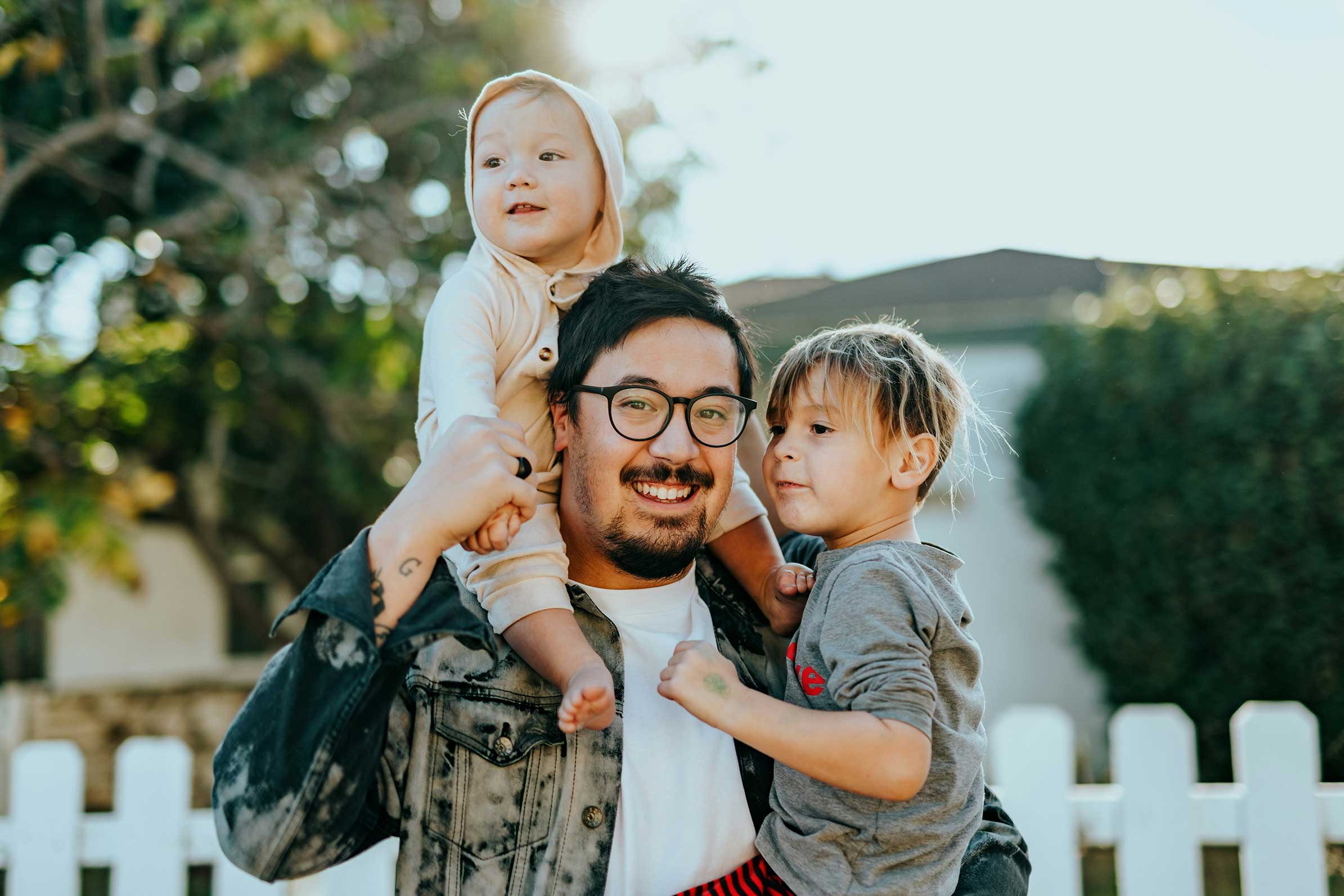 father with two young sons on his shoulders