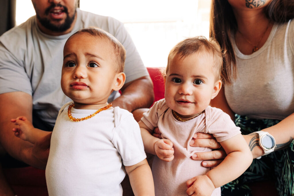 An adult holding two young children, one resting against their shoulder