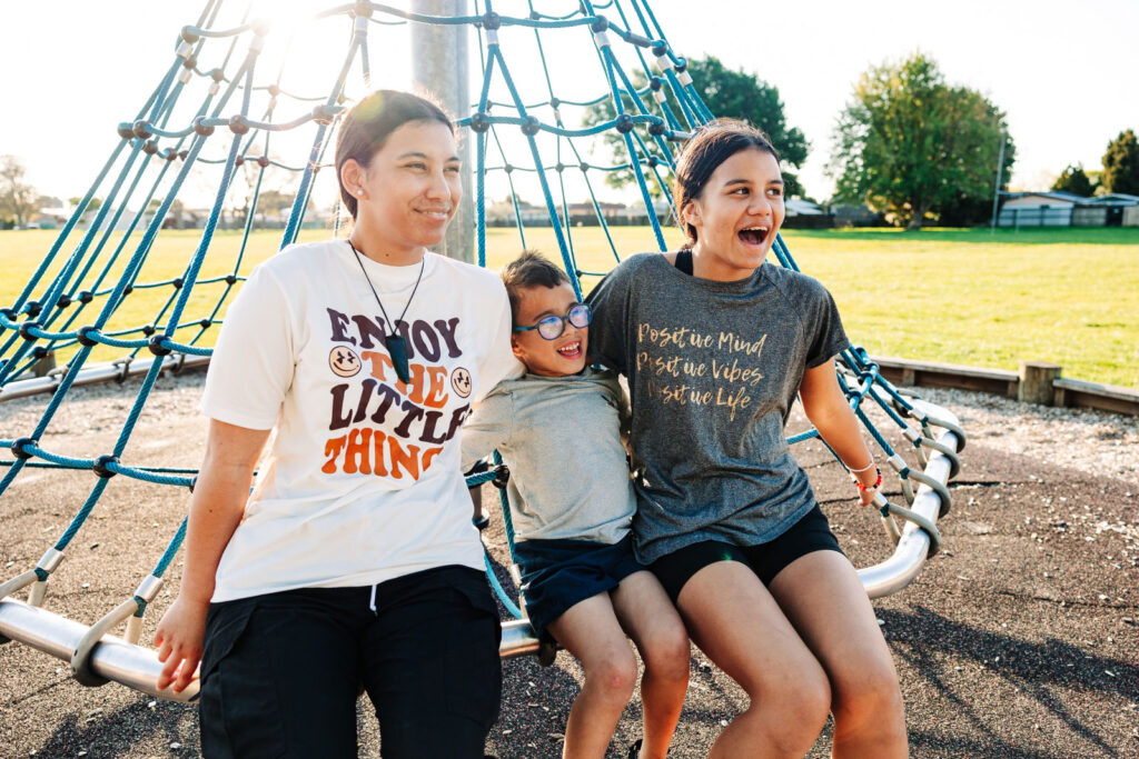 Two people sitting together on outdoor playground equipment, smiling and laughing